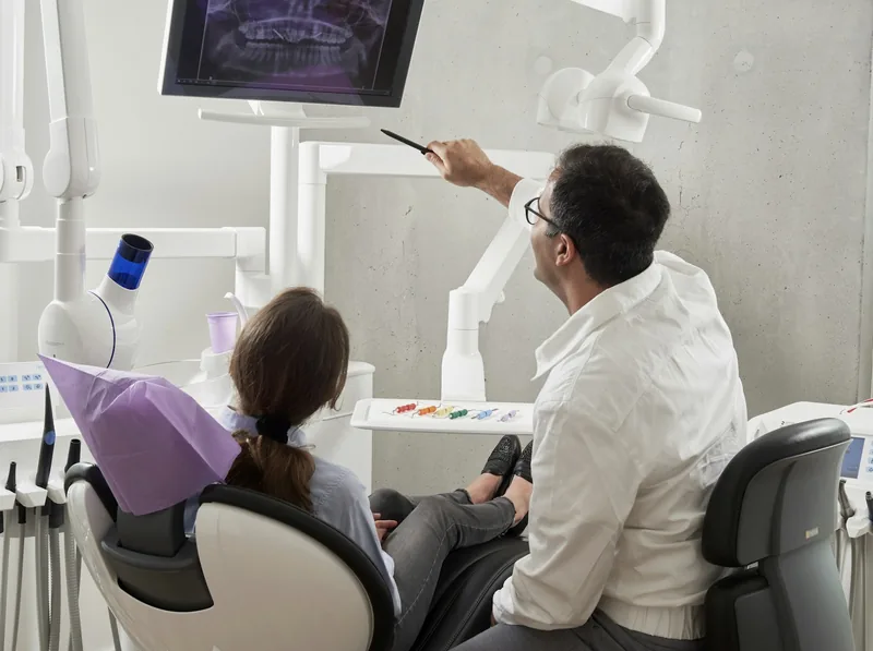 Odontólogo revisando una radiografía con el paciente en el sillón